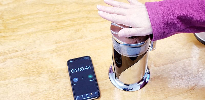 after 4 minutes of steeping your french press coffee, depress the plunger to push the grinds to the bottom